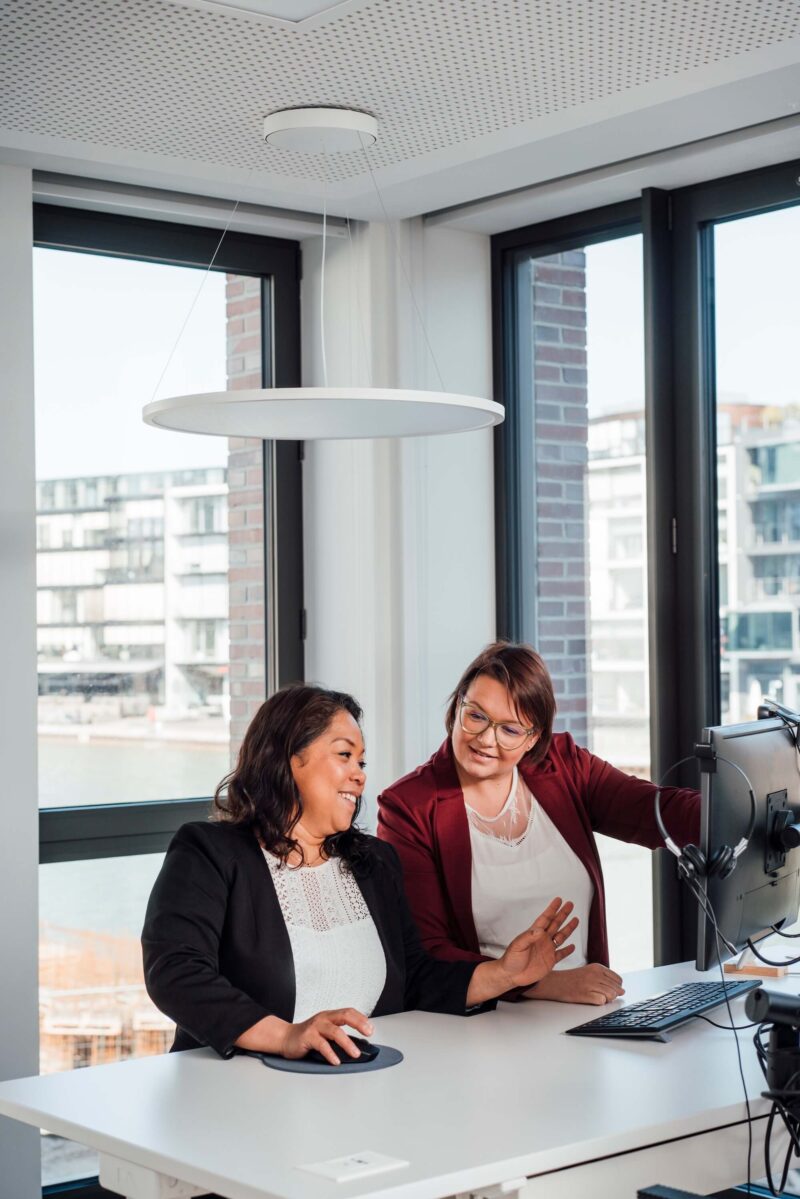 Zwei Mitarbeiterinnen diskutieren vor einem Monitor